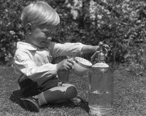 Small boy pouring himself a drink from a so