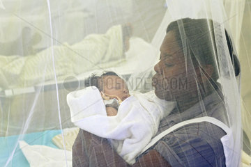 Carrefour  Haiti  lokale Krankenschwester mit Baby im Arm unter einem Moskitonetz