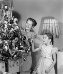 Woman and girl decorating a Christmas tree  c 1948.