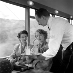 Waiter serving drinks to two female passengers  May 1953.