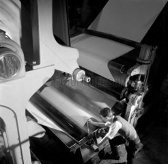 Making paper: a process worker inspecting rollers of production machine.