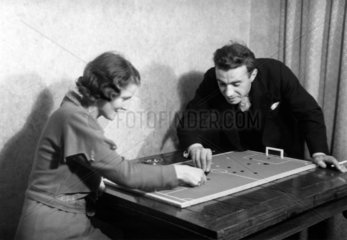 Couple playing tiddlywinks  c 1920s.