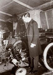 C S Rolls looking at the engine of a motor car in his garage  c 1900.