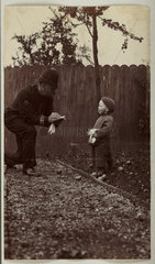 Policeman 'arresting' a small boy for scrumping apples  c 1915.