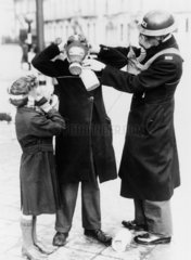 Policeman adjusting childrens' gas masks  Brighton  17 February 1941.