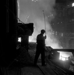 Steelworker silhouetted against blast furnace flames Consett  1957.