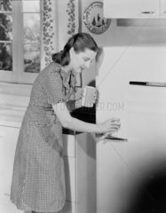 Woman cleaning the fridge  c 1955.