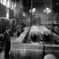 Workers dip long lengths of steel tubes in to acid pickling bath  1958.