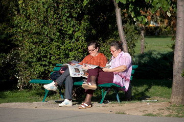 Bukarest  Rumaenien  zwei aeltere Frauen sitzen auf einer Parkbank und lesen Zeitung