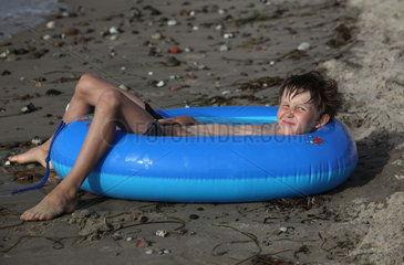 Kaegsdorf  Deutschland  Junge liegt in einem mit Wasser gefuellten Schlauchboot am Strand