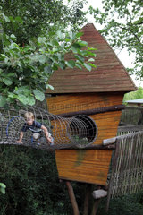 Marlow  Deutschland  Junge auf einem Spielplatz klettert durch eine Gitterroehre