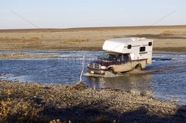 Coldfoot  USA  Truck Camper durchquert einen Fluss am Dalton Highway