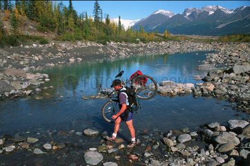 McCarthy  USA  Mountainbiker ueberquert einen Fluss im Wrangell-St.-Elias-Nationalpark