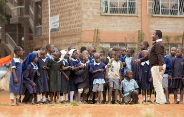 Nairobi  Kenia - Schueler und Schuelerinnen in Schuluniformen stellen sich auf dem Schulhof des St. John’s Community Centers Pumwani vor einem Lehrer in Reihe auf.