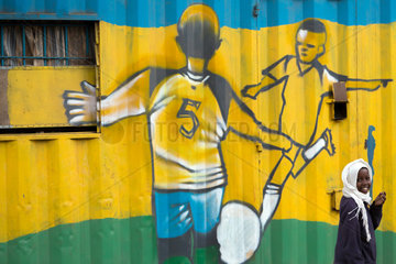 Nairobi  Kenia - Schuelerin im St. John’s Community Center Pumwani. Im Hintergrund eine  mit einem Fussballmotiv bemalte Hauswand.
