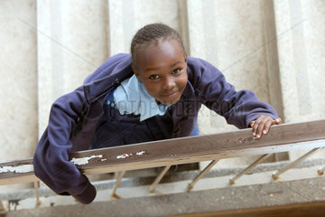 Nairobi  Kenia - Schuelerin in Schuluniform steht im Treppenhaus des St. John’s Community Centers Pumwani und schaut zum Betrachter.