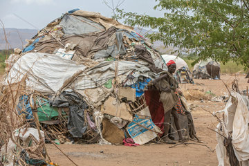 Kakuma  Kenia - Am Rande des Fluechtlingslagers Kakuma. Ein junger Mann steht vor seiner  von alten Plastikplanen  Decken  Kartons bedeckten Huette.