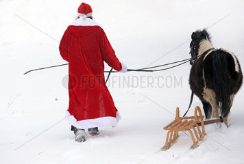 Oberoderwitz  Weihnachtsmann fuehrt sein eingespanntes Shetlandpony durch den Schnee
