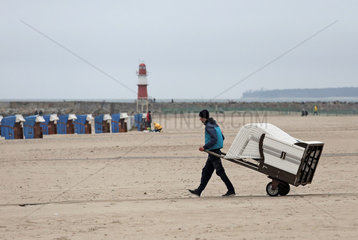 Warnemuende  Mann bringt einen Strandkorb an den Strand