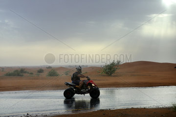 Dubai  Vereinigte Arabische Emirate  Quadfahrer bei Regen in der Wueste