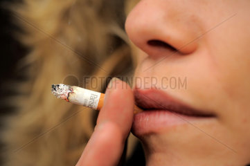 Junge Frau raucht eine Zigarette  Schaerfe auf Zigarette.