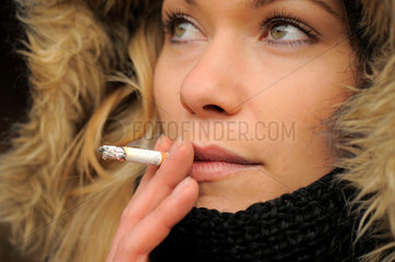 Junge Frau raucht eine Zigarette  Schaerfe auf Mund  Auge.