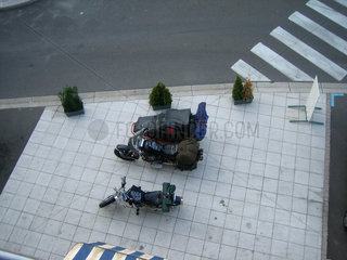 Zwei Reise - Motorraeder stehen auf einem Platz vor einem Hotel.