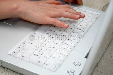 Eine Kinderhand schreibt auf einer Computertastatur.