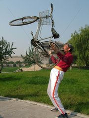China  ein Rentner hebt ein Fahrrad mit seinen Zaehnen