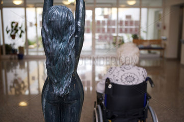 Rollstuhlfahrerin neben Skulptur