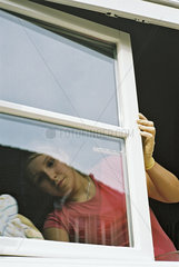 junge Frau beim Fensterputzen