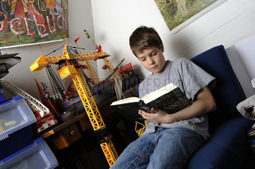 Junge liest Buch im Kinderzimmer