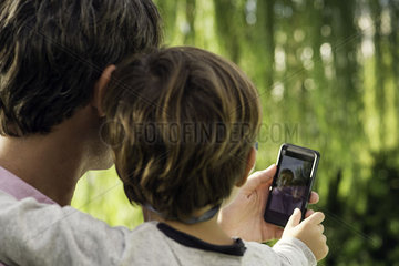 Father and son posing for photograph with smartphone