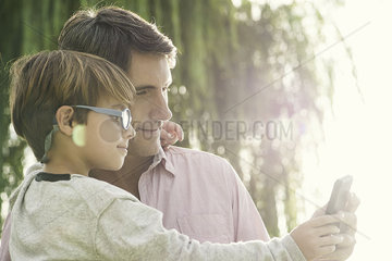 Father and son posing for photograph with smartphone  overexposure