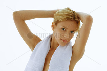 Woman with towel around neck  hands behind head  portrait