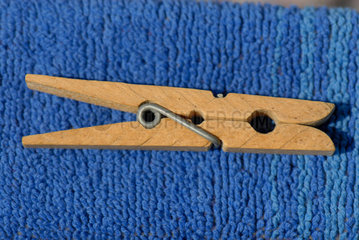 Waescheklammer aus Holz liegt auf blauem Badetuch.