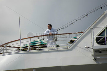 Der Koch (?) an der Reling auf Deck eines Schiffes.