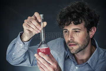 Man looking at liquid in conical flask