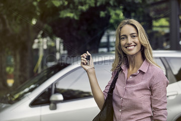 Young woman holding car keys  smiling cheerfully  portrait