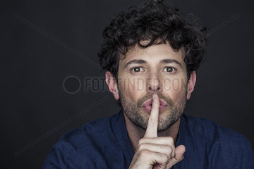 Man silencing with finger held to lips