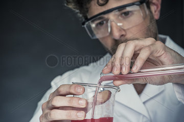 Scientist pouring liquid from test tube into beaker