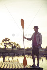Man standing on dock  holding oar