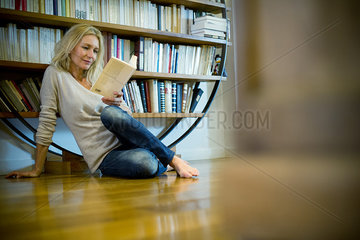 Mature woman relaxing with book at home