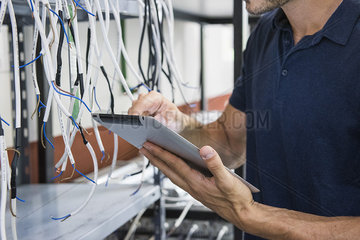 Electrician using digital tablet while inspecting equipment