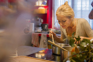 Mature woman smelling food while cooking