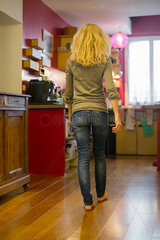 Woman walking toward kitchen at home  rear view