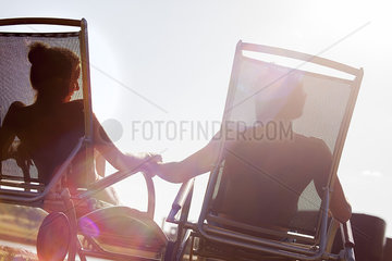 Couple relaxing together in deckchairs