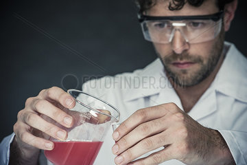 Scientist pouring liquid into test tube in lab
