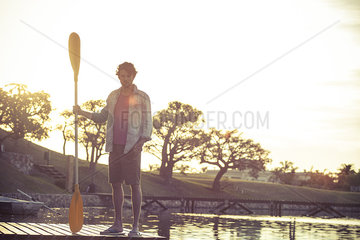 Man standing on dock with oar