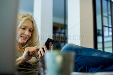 Mature woman relaxing with smartphone